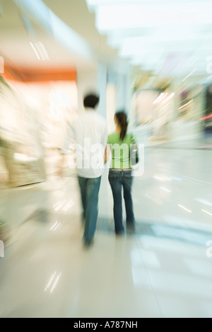 Couple walking through shopping mall, rear view, full length Stock Photo