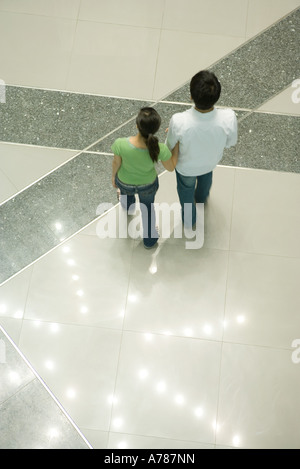 Couple walking past star-shaped light pattern on floor, high angle view Stock Photo