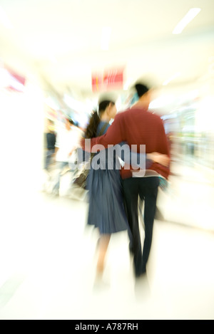 Couple walking through shopping mall, rear view, full length, blurred motion Stock Photo