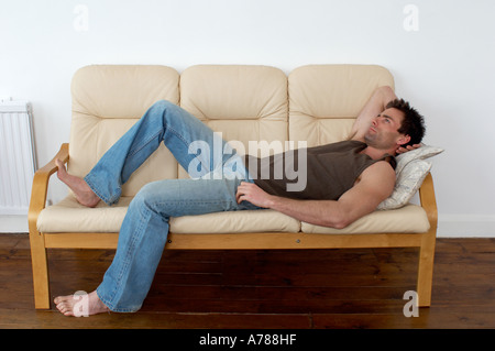 man resting and thinking laying on a sofa resting taking a break Stock Photo