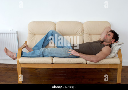 man resting and thinking laying on a sofa resting taking a break Stock Photo