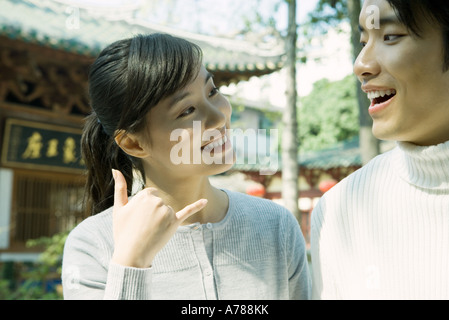 Woman standing next to man, making phone gesture, traditional Chinese building in background Stock Photo