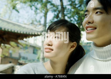 Couple standing side by side, looking out of frame, traditional Chinese building in background Stock Photo