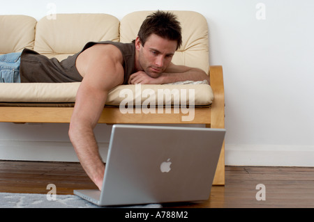 man on sofa working on a laptop computer home ofice working from home Stock Photo