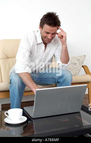 man on sofa working on a laptop computer home office working from home Stock Photo