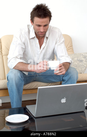man on sofa working on a laptop computer home office working from home Stock Photo