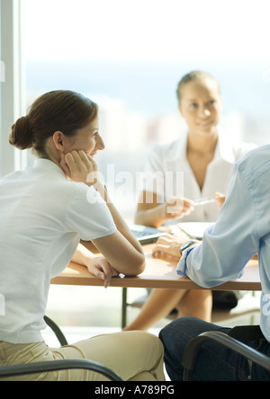 Young couple sitting across table from young female professional Stock Photo