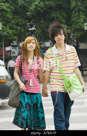 Young couple crossing street, holding hands, three quarter length Stock Photo