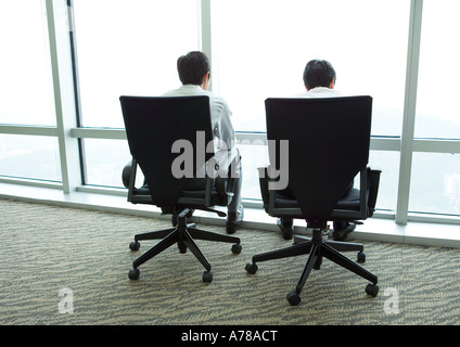 Two businessmen sitting in armchairs by window, rear view Stock Photo