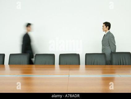 Businessman standing, facing associate arriving in conference room Stock Photo