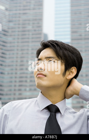Businessman with hand on back of neck, looking up and frowning Stock Photo