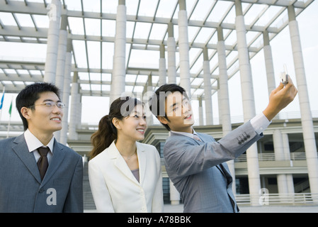 Businessman taking photo of self and two colleagues with cell phone Stock Photo