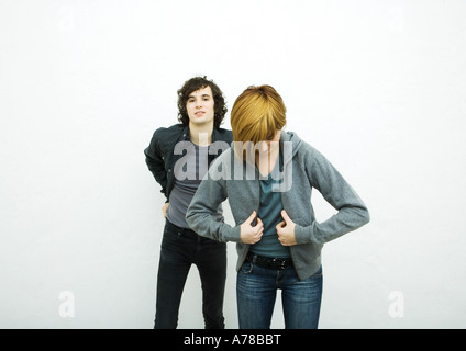 Two young adults putting on jackets, white background Stock Photo