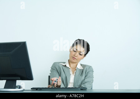 Businesswoman holding yinyang balls, sitting at desk Stock Photo