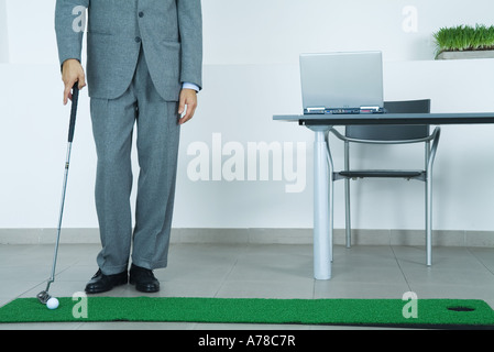 Businessman putting on artificial turf in office Stock Photo