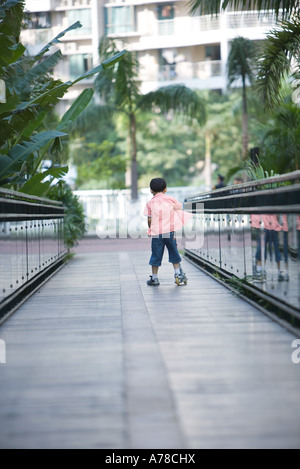Boy playing on push scooter, full length, rear view Stock Photo