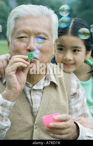 Girl with grandfather blowing bubbles