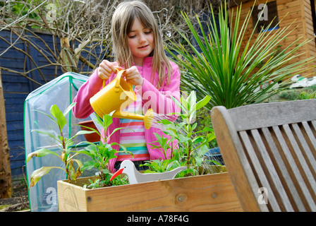 young girl with watering plants in garden Stock Photo