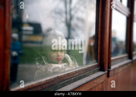 Baby child behind a window with reflections on the glass in an old fashioned railway train. Dalhem Railway Museum Gotland Stock Photo