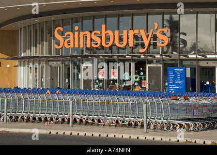 London large stack of Sainsburys supermarket trolleys in front of store entrance includes Stock Photo