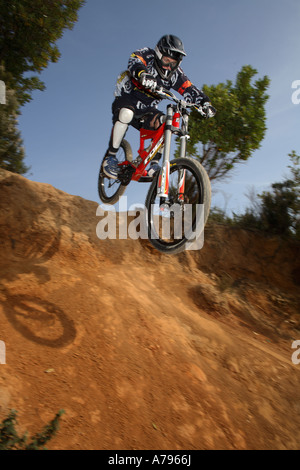 Downhill Mountain Bike Rider Comes over the Edge Stock Photo
