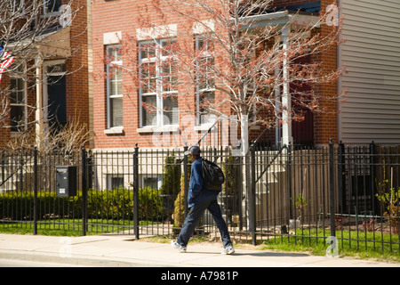 CHICAGO Illinois African American boy with backpack walk past red brick single family homes street in Old Town neighborhood Stock Photo