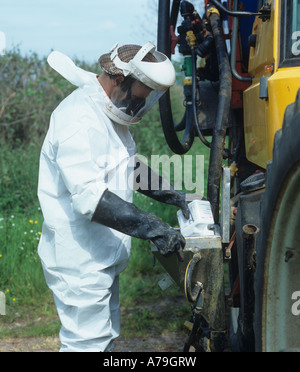 A spray operator in full safety clothing pouring chemical into the ...
