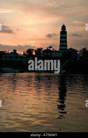 Hopetown Light at Sunset: The famous red and white lighthouse at Hopetown in silhouette and a reflection in the calm harbour Stock Photo