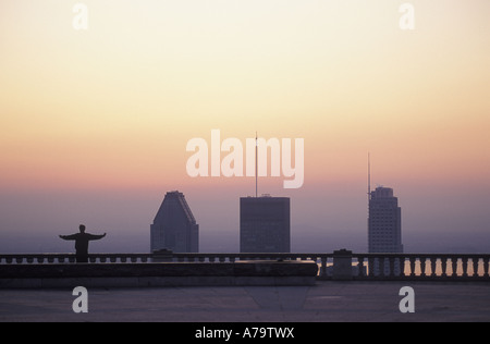 Silhouette of one man doing his morning ritual, stretching from Mont Royal  high above the Montreal skyline. Stock Photo