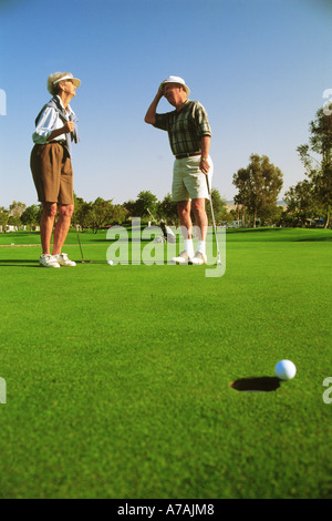 Couple in their 70s just missing putt while playing golf in Palm Springs, California Stock Photo