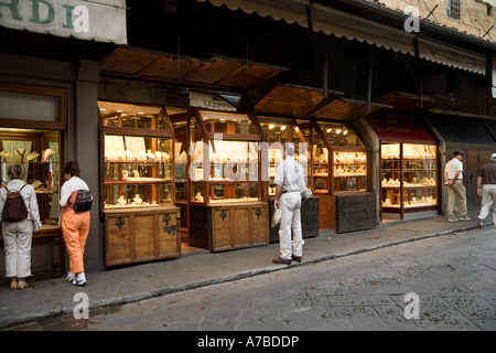 Potential customers gaze into windows of some of the many jewelry shops open on Ponte Vecchio bridge Florence Italy Stock Photo