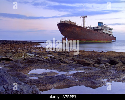 SHIPWRECK BEACHED ABANDONED Rusting shipwreck polluting pollution in shallow water in volcanic rocky cove Lanzarote Canary Islands Spain Stock Photo