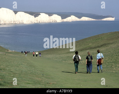 Seven Sisters white chalk cliffs landscape blue sky sunny day at Seaford Head groups of walkeron grass downs English Channel East Sussex England UK Stock Photo