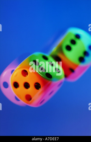 two colourful dice tumbling against a blue background Stock Photo