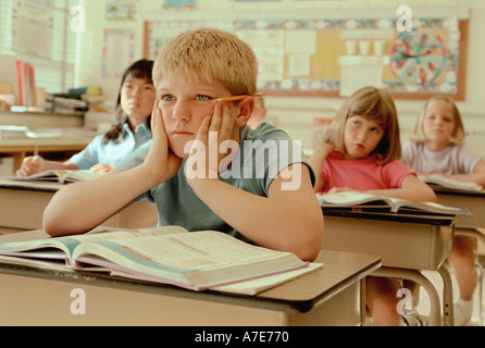 Bored Male Elementary School Pupil At Desk Stock Photo - Alamy