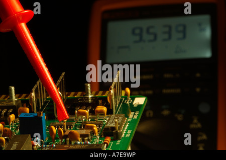 Industrial printed circuit board being checked with a modern digital multimeter. Stock Photo