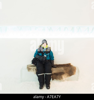 Female dressed in warm winter clothes sitting in the reception of the Ice Hotel at Kiruna the Arctic Circle region of Sweden Stock Photo