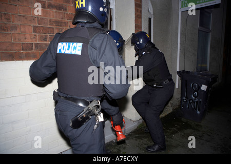 Police enter a house after breaking down a front door during a raid on suspected drugs dealers in Hull East Yorkshire Stock Photo