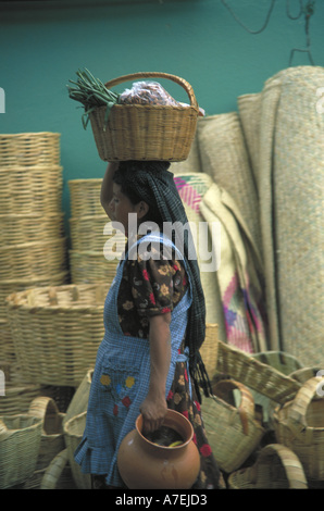 Mexico, Oaxacan woman in traditional attire balancing groceries while carrying pottery Stock Photo