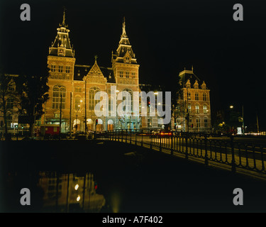 HOLLAND North Amsterdam Rijksmuseum illuminated at night beyond a bridge over a canal reflected in the water Stock Photo