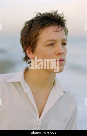 Young man standing on beach looking out to sea Stock Photo