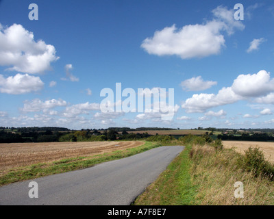 Big sky above narrow Suffolk country road passing through open agriculture unfenced farmland near Lavenham blue sky sunny day East Anglia England UK Stock Photo