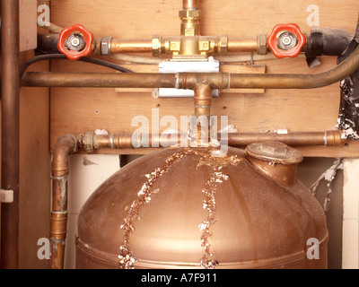 Inefficient old style unlagged copper hot water cylinder & pipes in dismantled airing cupboard prior to replacement showing signs of leaks Stock Photo