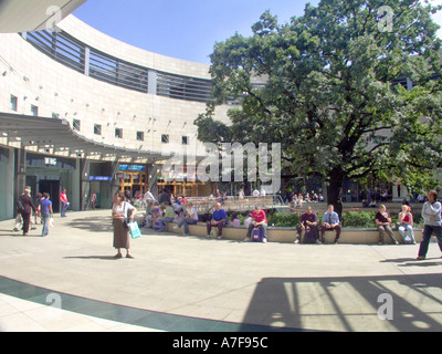 Milton Keynes part of New Town centre curved shopping façade with shoppers sitting below large tree providing some shade Buckinghamshire England UK Stock Photo