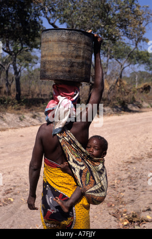 Metassuela Mozambique  Africa Mother walking home after collecting water with baby on her back Stock Photo