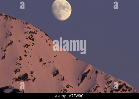 Alaska, Turnagain Arm Moon rises over snow-covered Kenai Mountains Stock Photo