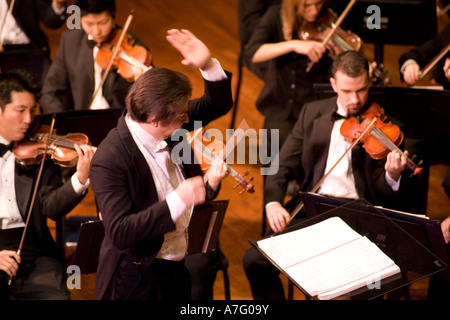 Music Director Kimo Furumoto directs student musicians or the California State University Fullerton Orchestra in a concert Stock Photo