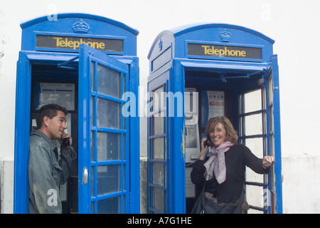 MR WOMAN AND MAN IN BLUE PHONE BOXES  ST-PETER PORT   GUERNSEY  CHANNEL ISLANDS GREAT-BRITAIN Stock Photo