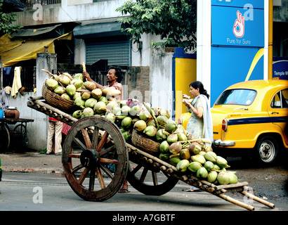 PKB77911 Coconut seller with handcart and woman drinking coconut water Calcutta India Stock Photo