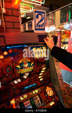 Playing a penny fruit machine in a seaside amusement arcade, UK Stock Photo